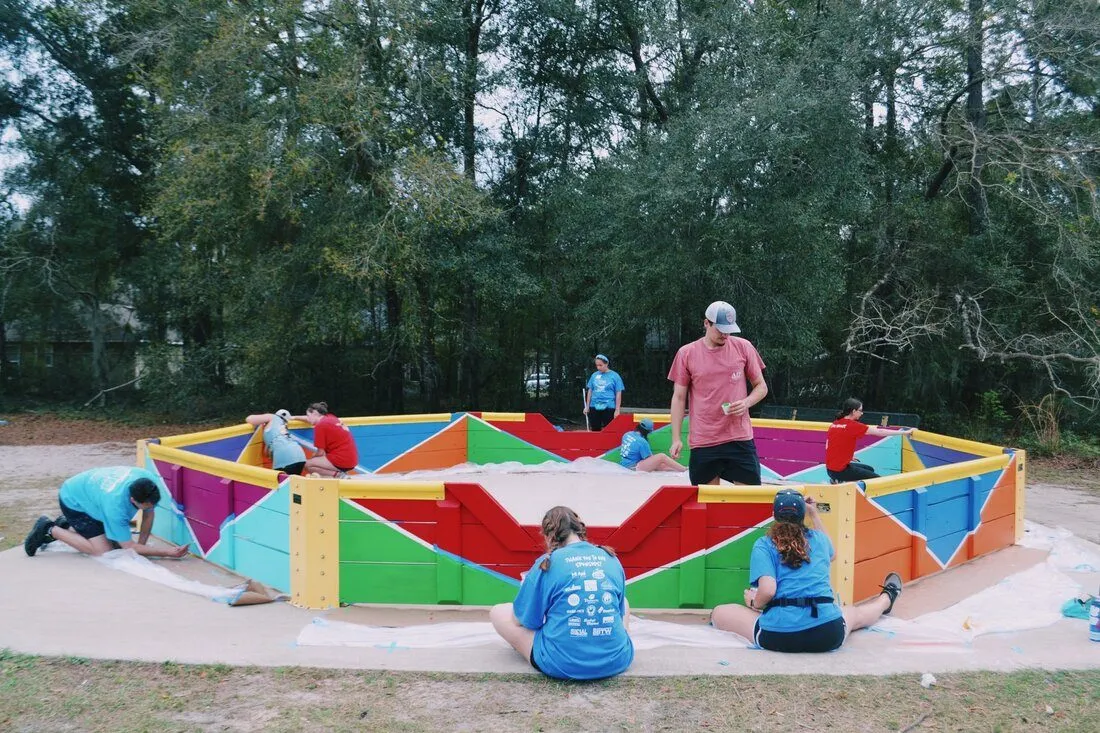 Volunteers painting the rainbow chevron panels of the new gaga ball pit