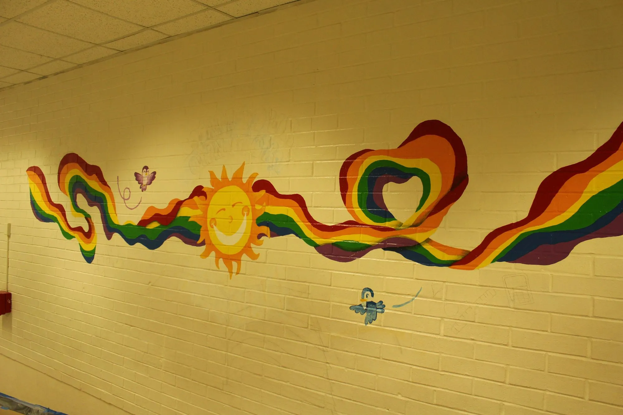 The finished rainbow ribbon and smiling sun mural running the length of the corridor