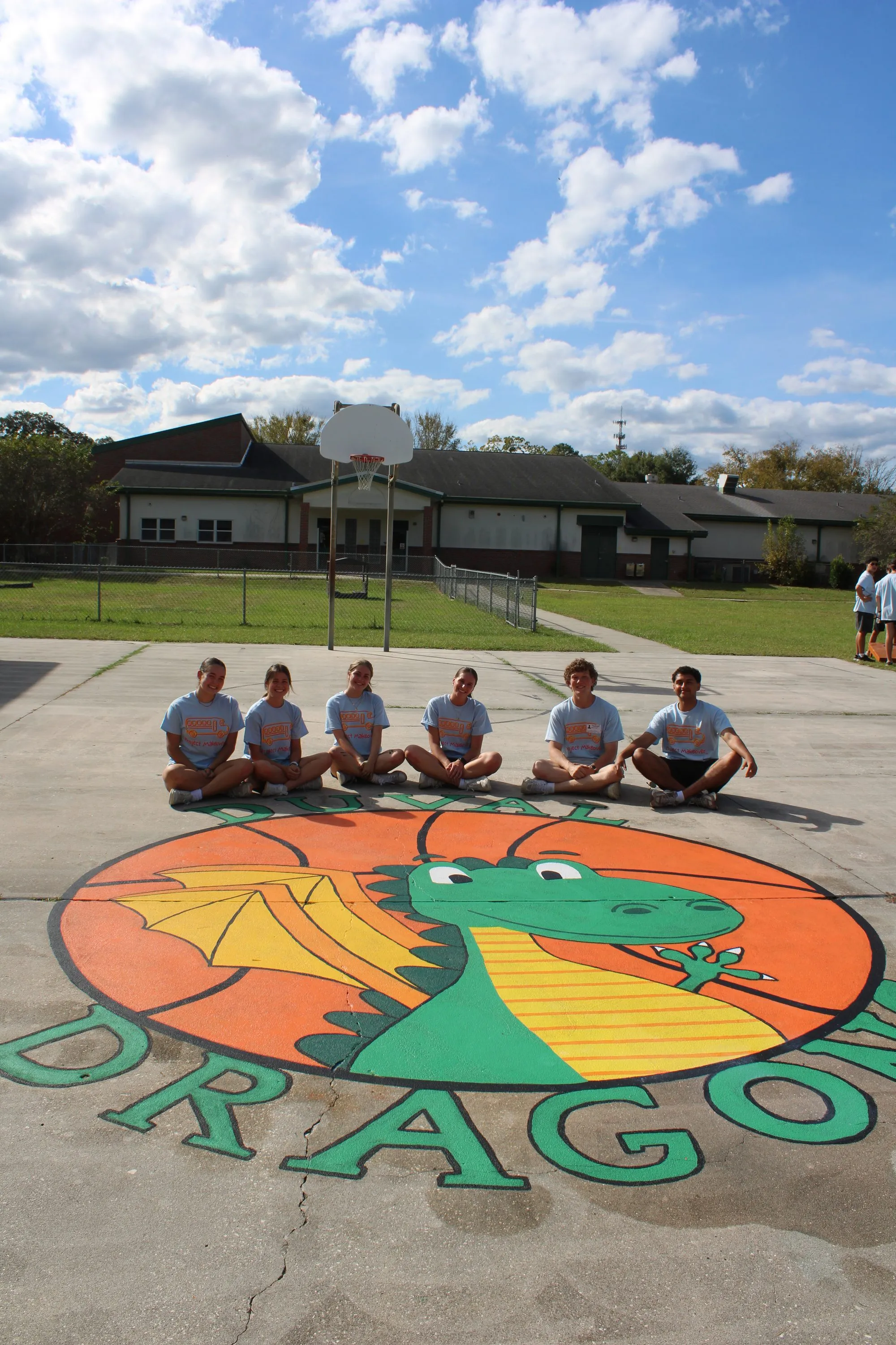 USF volunteers seated behind a freshly painted playground mural