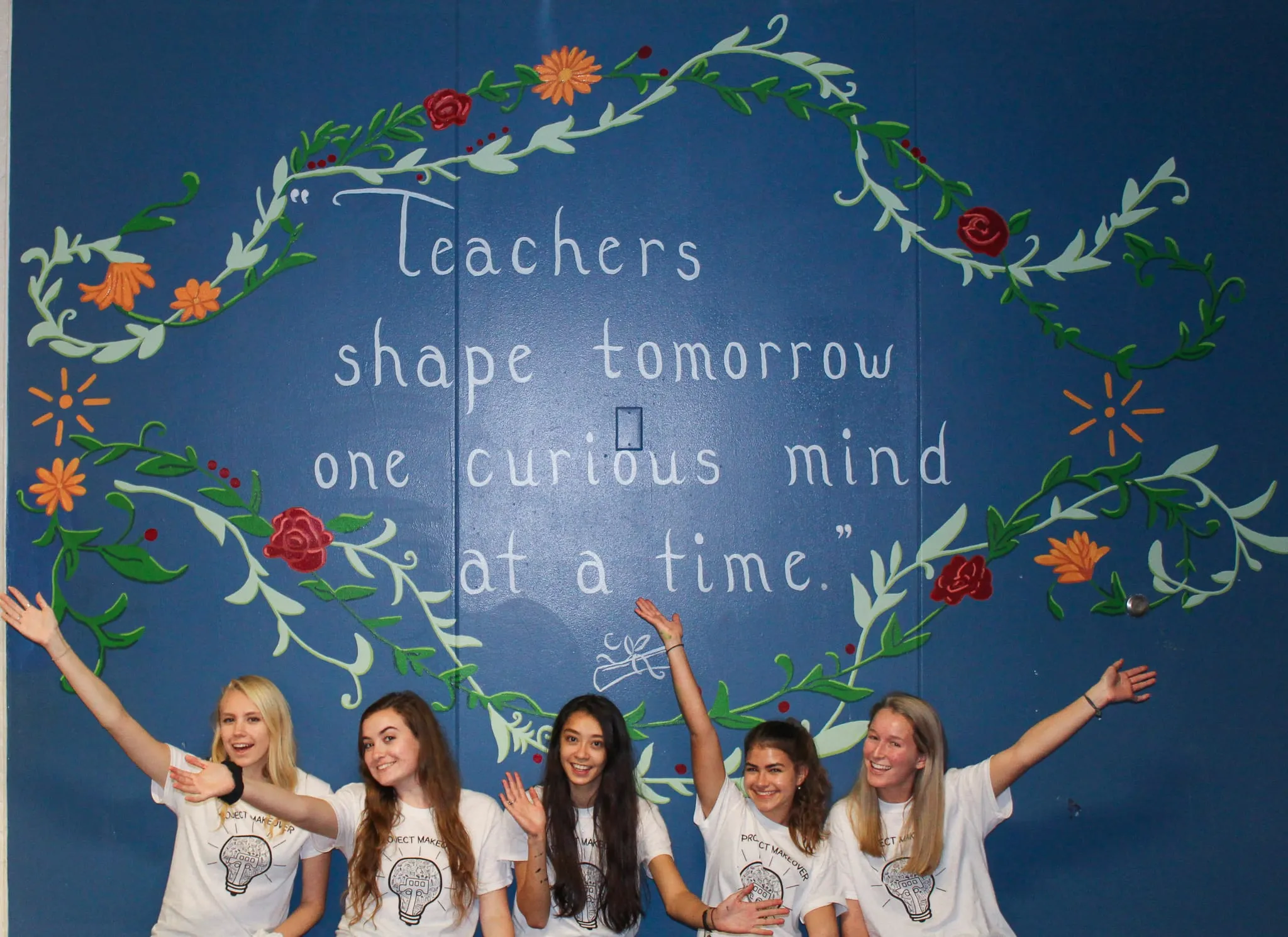 A colorful teachers-and-students mural painted across a school hallway wall